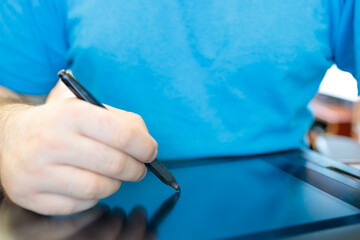 man draws with a stylus to draw on a tablet