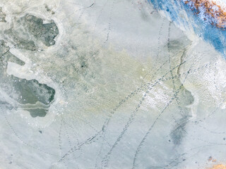 Flight over frozen lake breaking ice, Lithuania. Aerial photography during winter season.