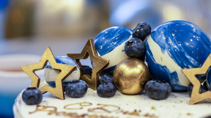 Handmade birthday cake on a blurred background with balloons and sparkles. Cheesecake cake, blue and gold accents. Festive background for postcard, holiday, birthday, anniversary, 18 years. 