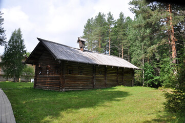 An old wooden house made of logs on a green meadow among the trees. 09 August 2020, Arkhangelsk, Russia