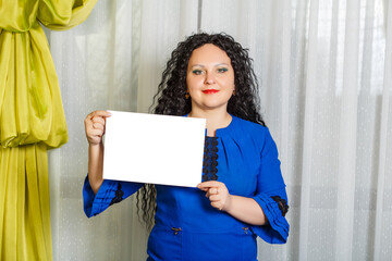 Curly joyful brunette woman holding a copy space plate in her hands.
