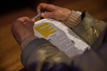 Old female hands holding the bible and pen, close up photo with book of Psalms in russian