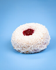 Coconut doughnut with jam on a blue background.