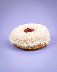 Coconut doughnut with jam on a purple background.