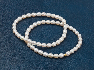 Luxury elegant baroque pearl bracelets on dark blue textured leather background