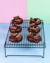Chocolate doughnut on cooling rack and pink, green and blue background.