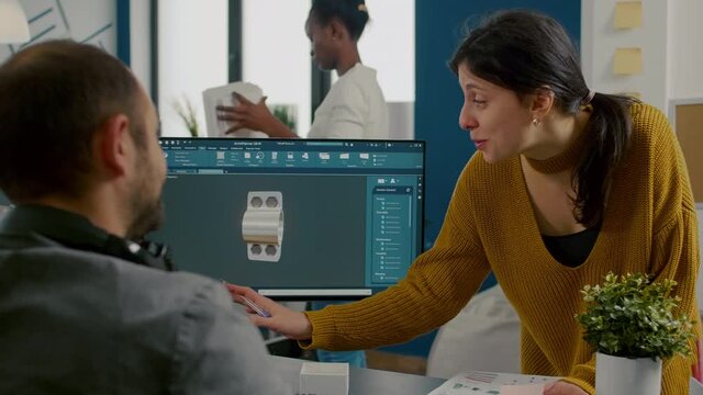 Industrial woman designer discussing with technician engineer working in CAD program, designing 3D prototype machine components. Designer director cheking and writting informations on sticky notes