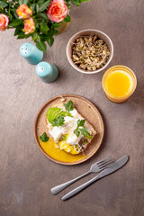 Fototapeta na wymiar Light summer breakfast - sandwich with avocado, cottage cheese, sprouted beans and poached egg with orange juice on the table