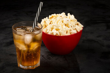 Bowl with salted popcorn and soda on the table.