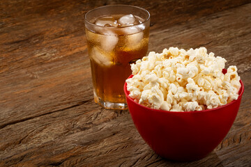 Bowl with salted popcorn and soda on the table.