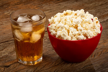 Bowl with salted popcorn and soda on the table.