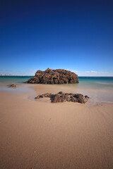 Beach with turquoise sea water with rocks. long exposure.