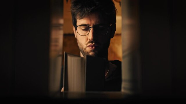 Ragazzo in biblioteca con occhiali prende il libro dalla libreria