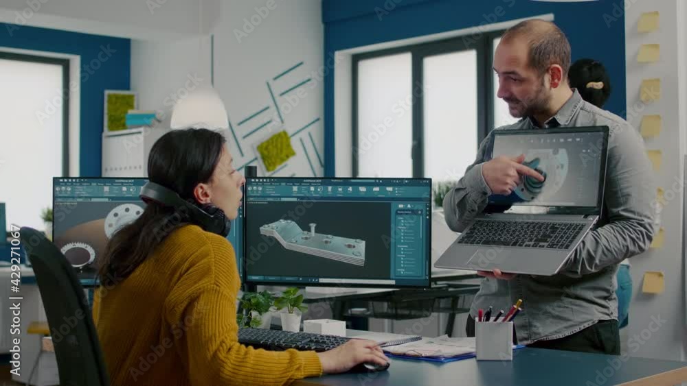 Poster engineer holding laptop and pointing on display showing to manager 3d gears image working in cad pro