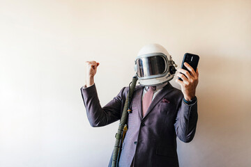Euphoric businessman with astronaut helmet using smartphone
