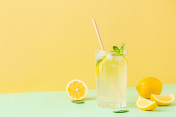 Lemon ice tea with mint leaves on bicolor background (yellow and green). Fresh exotic cocktail in...