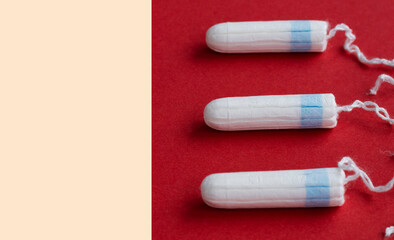 three female tampons lie on a bright red background. Feminine hygiene products. Copy space. High quality photo