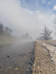 Close up of wet road in fog in mountainous terrain. Asphalt road after rain in foggy and cloudy weather.