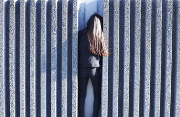 Une jeune fille tourne le dos au milieu de stries de ciment