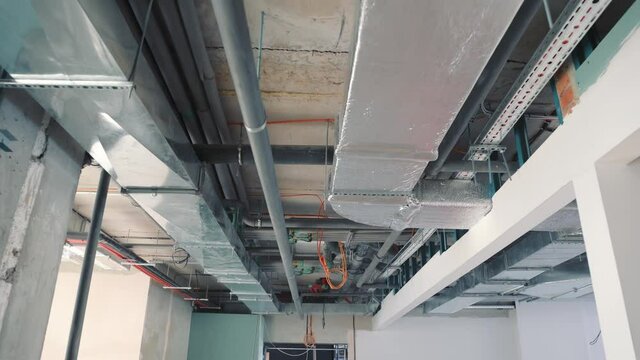 Pipes and ventilation on the ceiling of the building corridor. Switching of ventilation shafts and water pipes and heating of the building