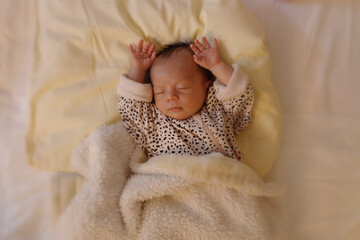 Un bébé dort avec les bras levés