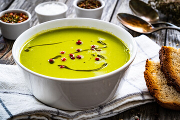 Cream green peas soup on wooden table 