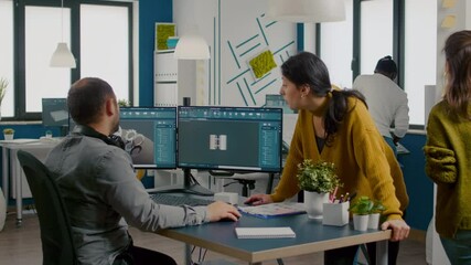 Team of engineers talking in front on pc with CAD software and two monitors working in start up company innovating an efficient eco-friendly motor prototype. Industrial architects sharing ideas.