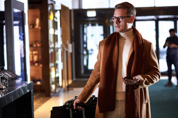 Businessman in coat goes to reception, arrived in hotel