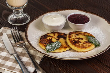 Cheesecakes with sour cream jam and coffee latte on a rustic background