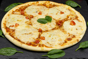 Pizza with mozzarella on a black background close-up with ingredients.