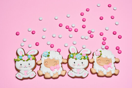 Pink pastel background with homemade gingerbread in form of cute rabbit and lamb. Tasty biscuits covered with colorful glaze. Easter concept. © serhiibobyk