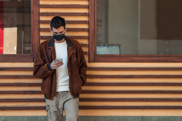young man with mask and mobile phone outdoors