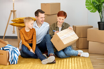 Fototapeta na wymiar Happy family moving to new place sitting holding marker pen writing carboard boxes