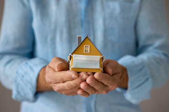 Senior Businessman Holding Model House Wearing Protective Medical Mask In Hands