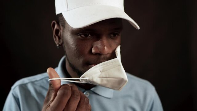 Young African American Ethnicity Man Putting On FP2 Face Mask For Coronavirus Protection. medium shot of new normality