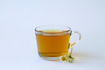mug of chamomile tea. glass cup of iced Herbal chamomile tea on a white table with copy space. cup of tea with fresh flowers and green leaves on white background.