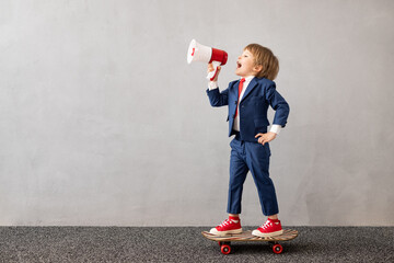 Happy child wearing suit riding vintage skateboard