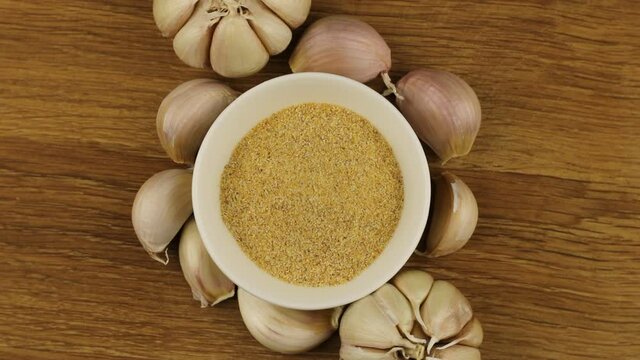 Ground garlic powder on the saucer and heads of garlic around rotates slowly.