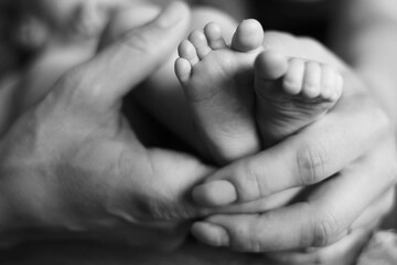 Mother's hands hold small baby legs