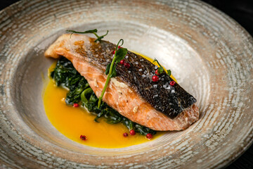Fish grilled, on a plate, on a dark wooden table

