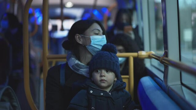 Parent and child riding bus during pandemic wearing covid-19 face mask