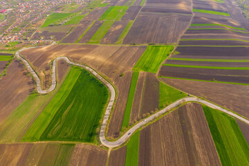 Fototapeta na wymiar Curvy road and empty agricultural fields in spring. 