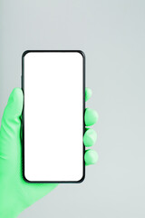 A smartphone with a clean white screen in the hand in a green medical glove close-up.