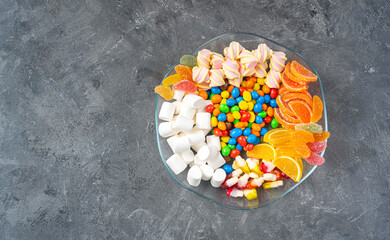 Plate with sweets, candies, marshmallows and marmalade. Top view. Copy space.