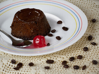 Tasty Creme caramel dessert or Coffee Flan with a cherry and a metal spoon on a plate decorated with coffee beans