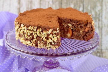Vegan raw chocolate cake with dates, almond nuts, mashed banana and cacao powder on cake stand