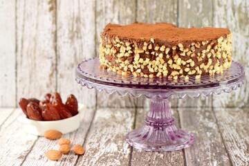 Vegan raw chocolate cake with dates, almond nuts, mashed banana and cacao powder on cake stand