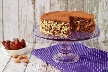 Vegan raw chocolate cake with dates, almond nuts, mashed banana and cacao powder on cake stand