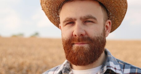 Close up portrait of handsome happy Caucasian farmer in hat looking at camera while standing in...