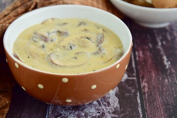 Cream of mushroom soup in a bowl on wooden background